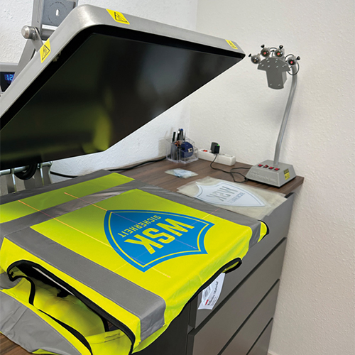eine gelbe Warnweste auf einem Schreibtisch Rheinpiraten Agentur in Rheinbreitbach, Bonn und Köln– Grafikdesign, Webdesign, Werbetechnik & Textilveredelung